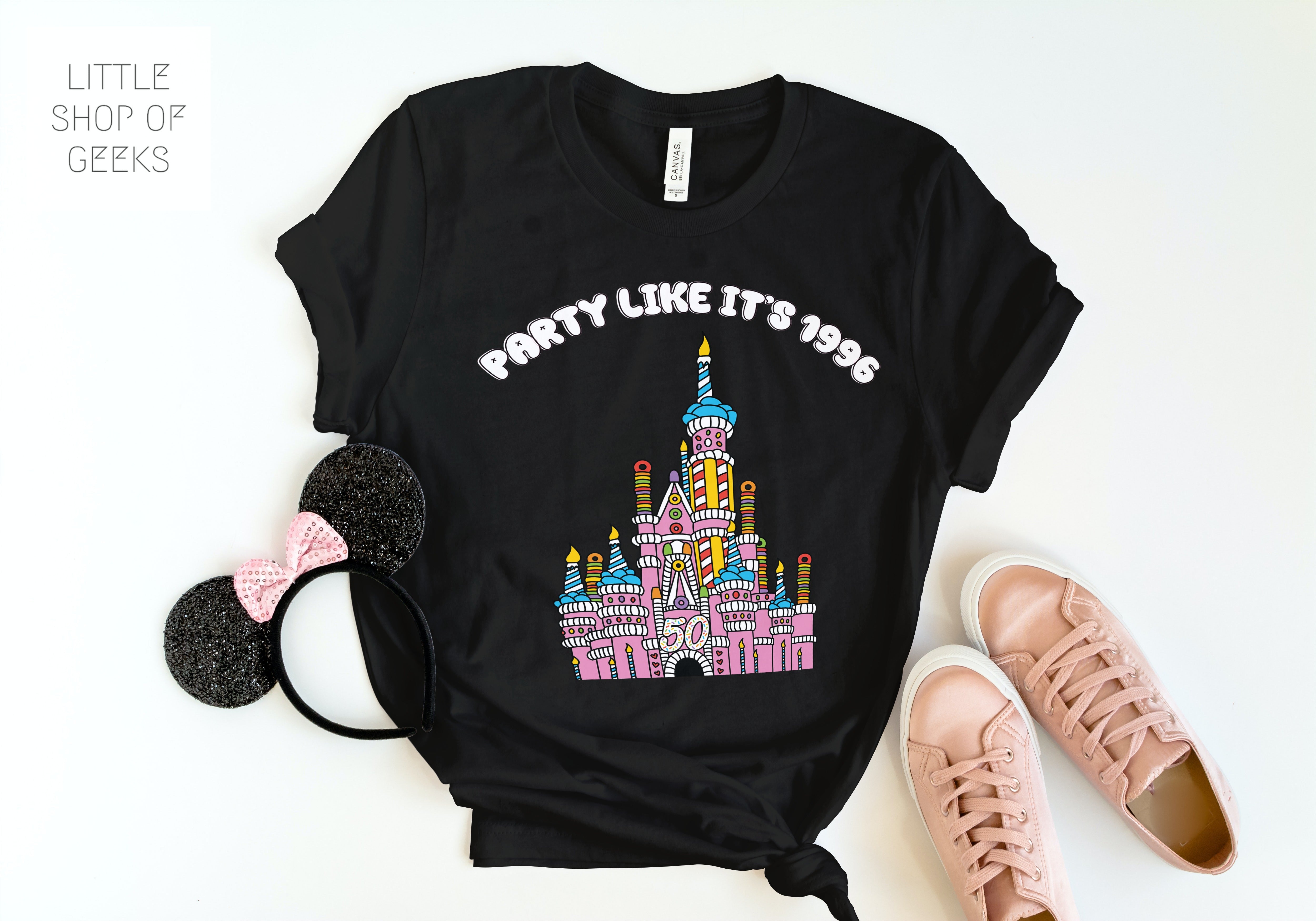 black shirt with cake castle illustration and party like its 1996 in bubble font in flat lay with mouse ears and pink sneakers